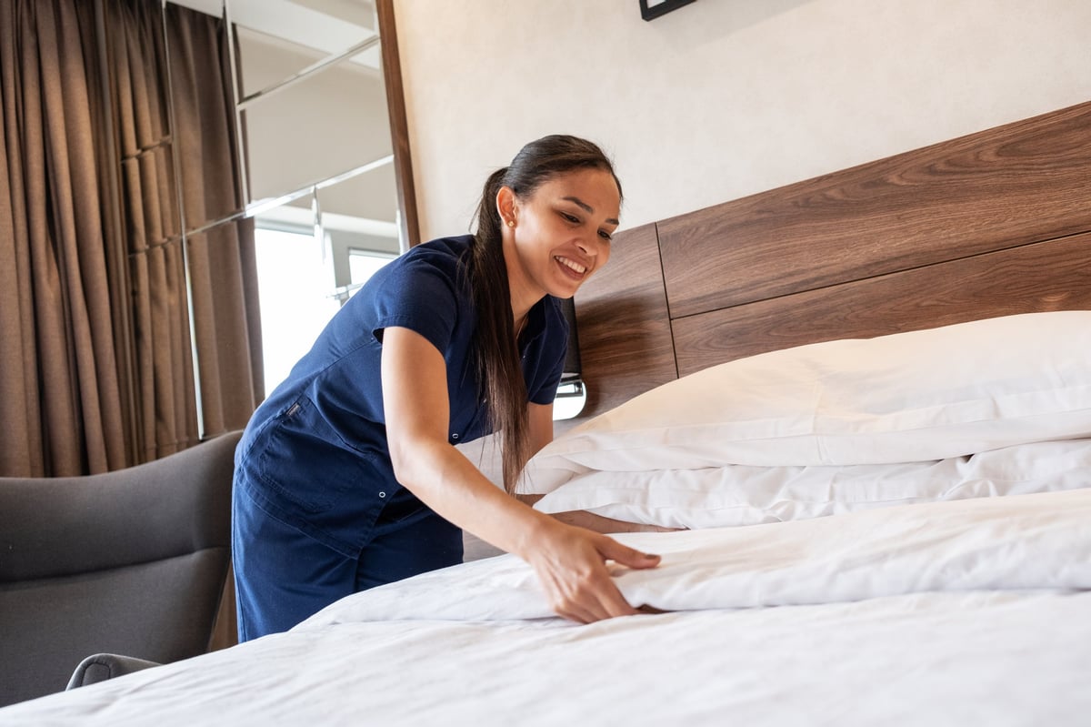 Professional cleaner preparing beds with fresh linens at a Reunion vacation home